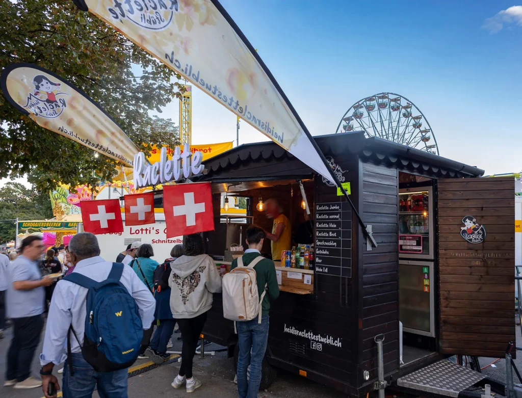 Holz-Foodtruck mit Schweizer Fahnen, Schweizer Raclette am Fest