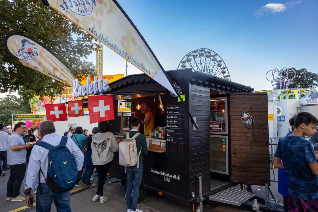 Holz-Foodtruck mit Schweizer Fahnen, Schweizer Raclette am Fest